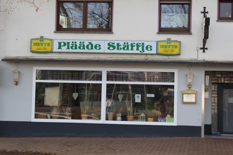Ein Geschäft mit dem Namen "Pläde Stäffje" auf der Vorderseite. Die Fenster sind gut sichtbar, und es gibt eine einladende Atmosphäre.