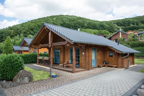 Ein gemütliches Ferienhaus im Landhausstil aus Holz mit blauen Fenstern. An der Wand ist die Hausnummer 4 sichtbar, dazu ein Schild mit der Bezeichnung "Ferienhaus".