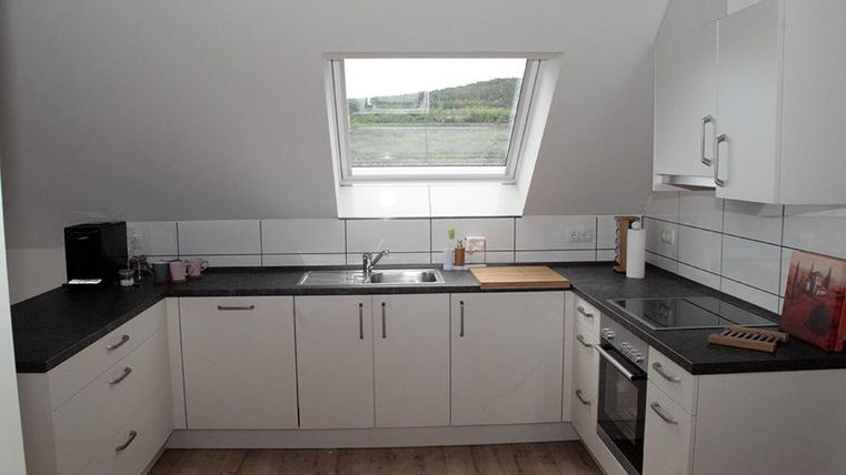 Eine moderne Küche mit weißen Schränken und schwarzer Arbeitsplatte. Das Fenster bietet einen Blick auf die Landschaft.