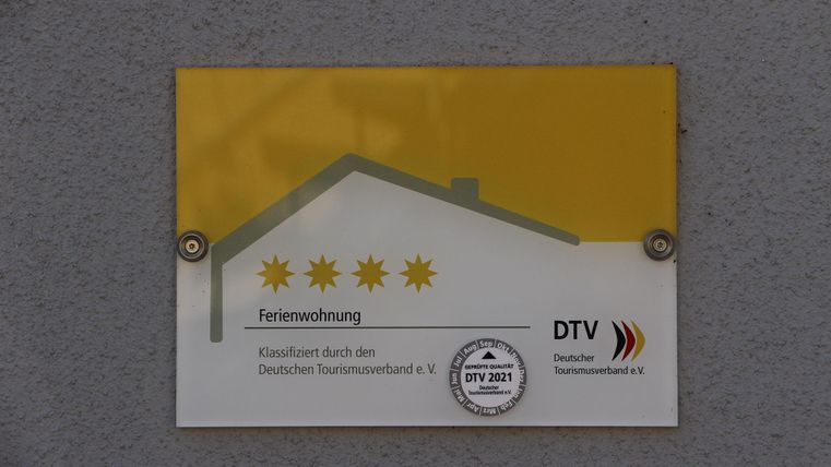 Ein Schild mit der Aufschrift "Ferienwohnung" und fünf Sternen. Das Schild ist vom Deutschen Tourismusverband zertifiziert.