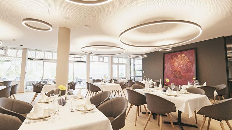 Ein modernes Restaurant mit eleganten Tischen und Stühlen. Das Licht ist hell und die Wände sind geschmackvoll dekoriert.