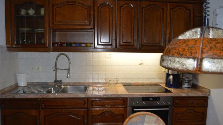Eine gemütliche Küche mit Holzschränken und einer hellen Arbeitsfläche. Der Bereich ist gut beleuchtet und enthält moderne Küchengeräte.