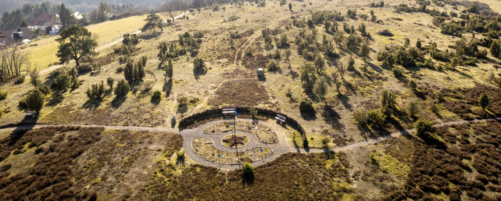 Blick auf eine h&uuml;gelige Landschaft mit B&auml;umen und einem kleinen Labyrinth am Wanderweg Traumpfad Wacholderweg., &copy; Eifel Tourismus GmbH, D. Ketz