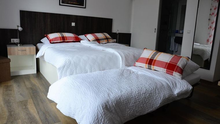 Ein gemütliches Schlafzimmer mit zwei Einzelbetten und karierten Kissen. Der Raum hat stilvolle Möbel und viel natürliches Licht.