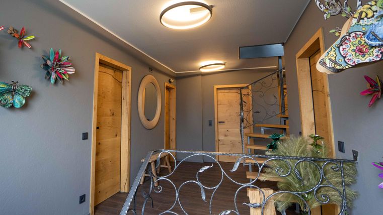 Ein moderner Flur mit grauen Wänden und Holzdetails. Bunte Wanddekorationen und eine Treppe verleihen dem Raum eine einladende Atmosphäre.