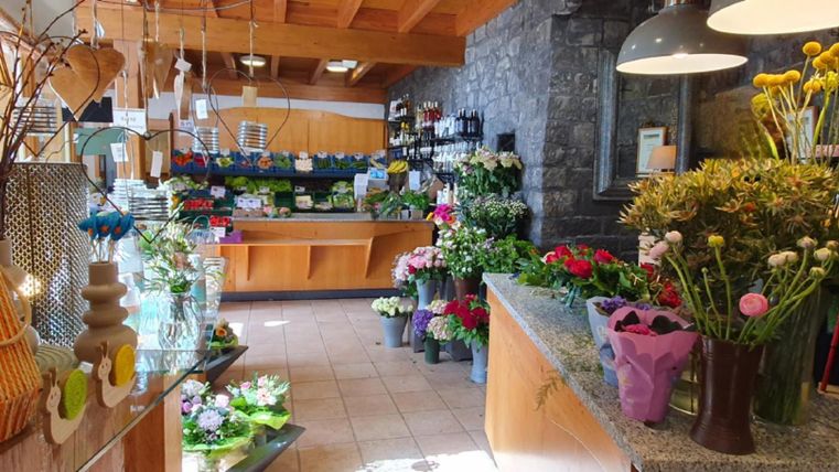 A floral shop with various flower arrangements and fresh flowers. The walls are made of stone, and the ceiling has wood paneling.