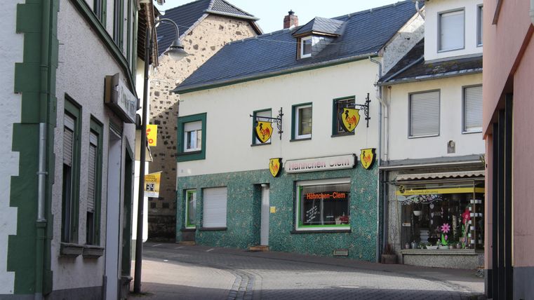 Ein ruhiger Stadtwinkel mit bunten Häusern und Geschäften. Die Straßen sind gut beleuchtet und bieten einen einladenden Blick.