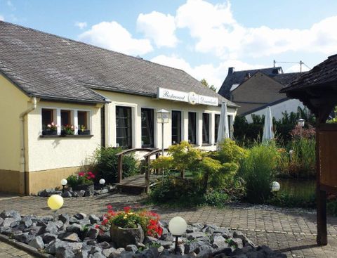 Ein charmantes Restaurant mit einem gepflegten Garten und bunten Blumen. Die Architektur ist einladend und harmonisch in die Umgebung integriert.