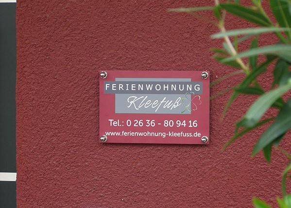 A sign with the inscription "Ferienwohnung Kleefuss". It includes contact details and the website.
