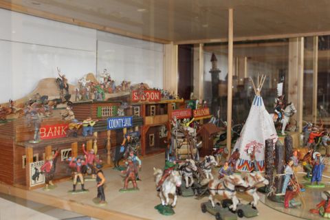 Eine detailreiche Sammlung von Spielzeugfiguren in einer Western-Szene. Sie zeigt ein Saloon, eine Bank und Indianerzelte mit Reitern und Pferden.