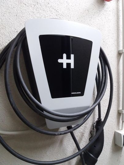 Eine moderne Ladestation für Elektrofahrzeuge an einer Wand. Kabel sind ordentlich aufgewickelt und bereit zur Nutzung.