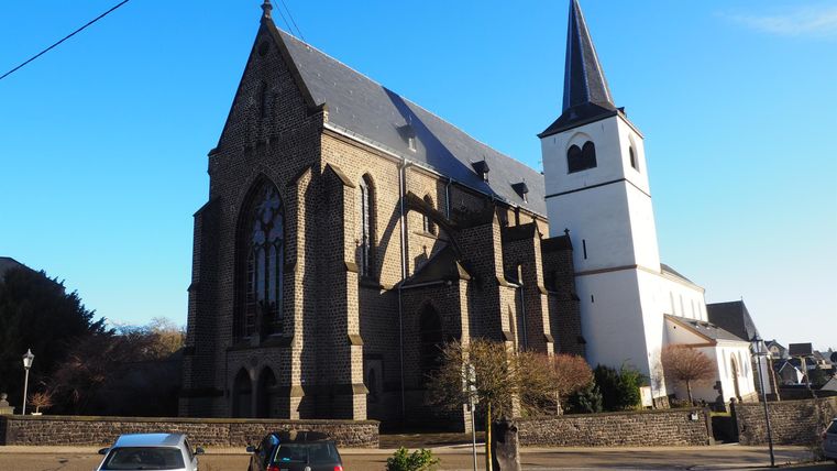 An impressive church with a tall tower and a beautiful window. The sky is clear and blue.