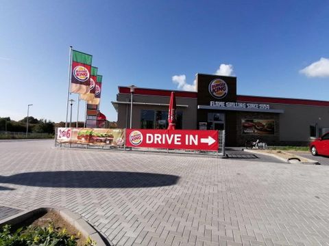 A Burger King restaurant with a drive-in facility. There are flags and a large advertising banner indicating the drive-in.