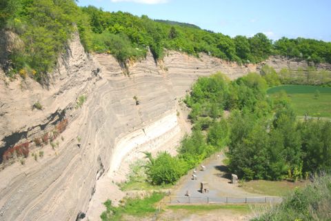 Eine beeindruckende Sandsteinwüste mit hohen Hängen und üppigem Grün. Wanderer erkunden den Bereich, umgeben von Natur.