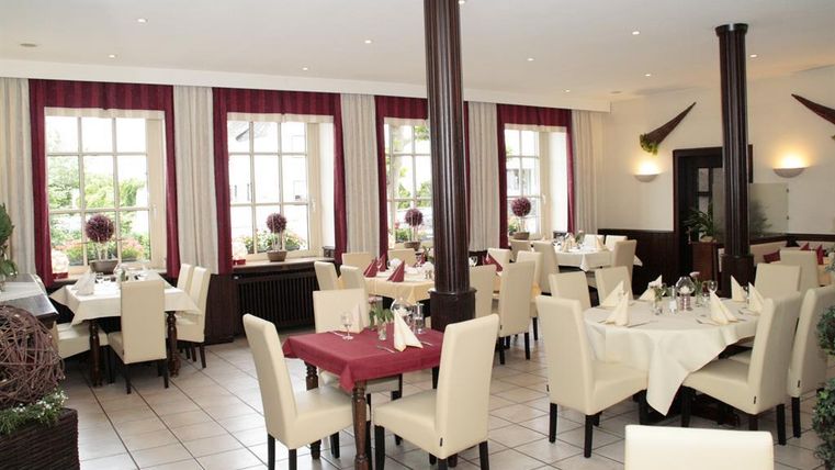 A bright restaurant with white tables and comfortable chairs. Large windows provide plenty of natural light and an inviting atmosphere.