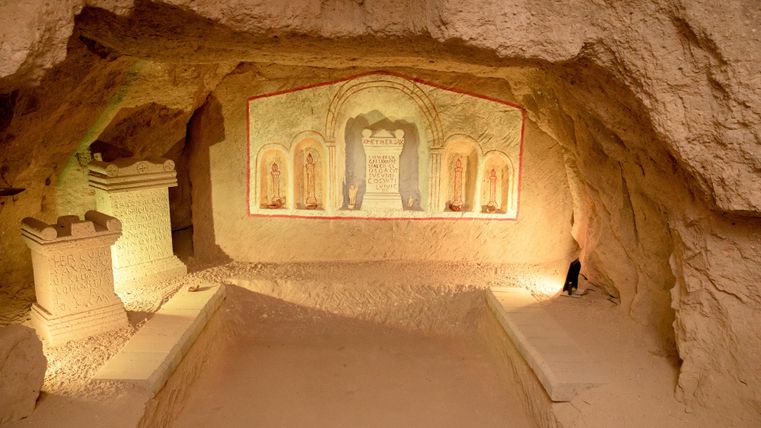Eine eindrucksvolle Höhle mit kunstvollen Wandmalereien und sanfter Beleuchtung. Die Umgebung ist aus natürlichem Gestein und strahlt eine mystische Atmosphäre aus.