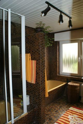Ein modernes Badezimmer mit einer Badewanne und einer Dusche. Die Wände sind mit geschmackvollen Fliesen dekoriert, und große Fenster sorgen für Tageslicht.