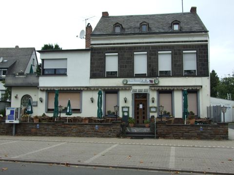 A traditional restaurant building with an inviting outdoor area. There are tables and sun umbrellas on the terrace.