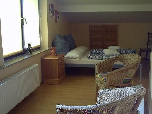 A cozy room with a bed and two chairs. Brightly lit by a window, the room offers a calm atmosphere.
