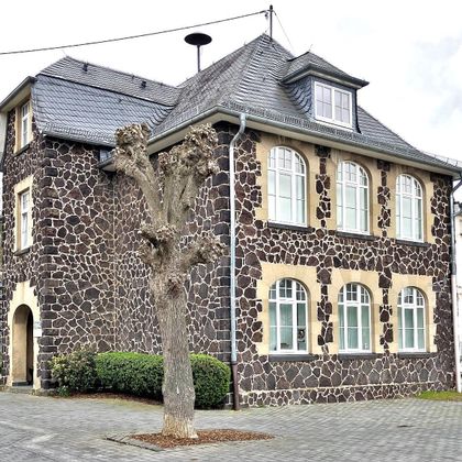 A historic building with a unique stone façade. It has large windows and a modern roof shape.