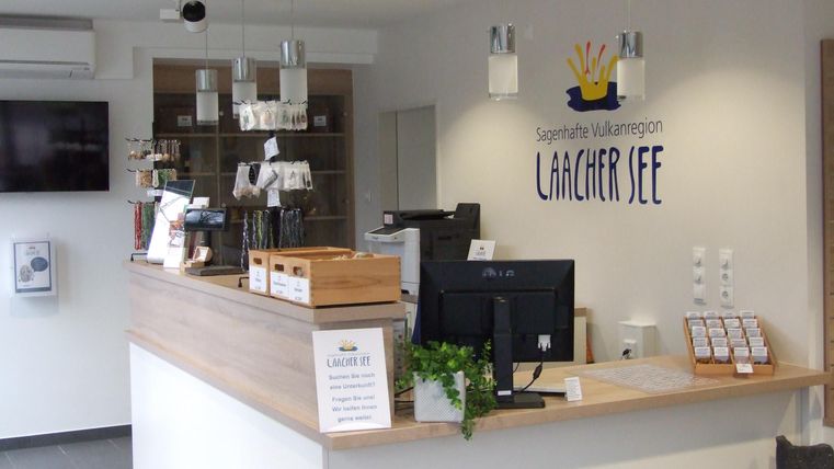 Ein moderner Empfangsbereich mit einem Holzschalter und einer freundlichen Atmosphäre. An der Wand befindet sich ein Schild mit dem Namen „Lagersee“.