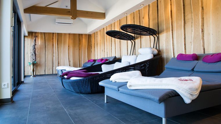 An elegant wellness room with comfortable loungers and warm wooden paneling. The atmosphere is relaxing and modern.