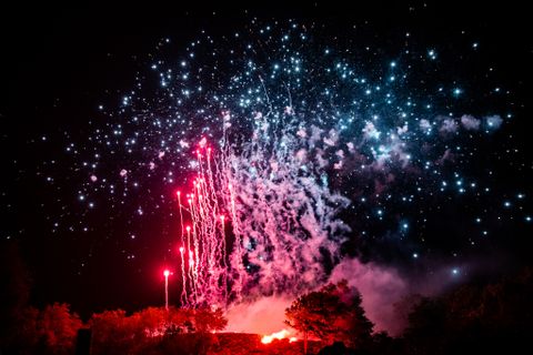 Luftaufnahme eines Höhenfeuerwerks. Die Funken des Feuerwerks sind rot. Die Umgebung leuchtet rot.