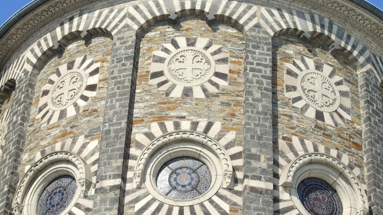 A decorative stone wall with round windows and ornate embellishments. The architecture features an interesting pattern and a clear structure.