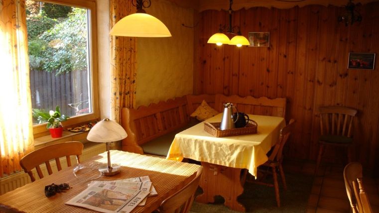 Ein gemütlicher Essbereich mit Holzvertäfelung und einem Tisch für mehrere Personen. Der Raum ist hell erleuchtet und bietet einen Blick auf den Garten.