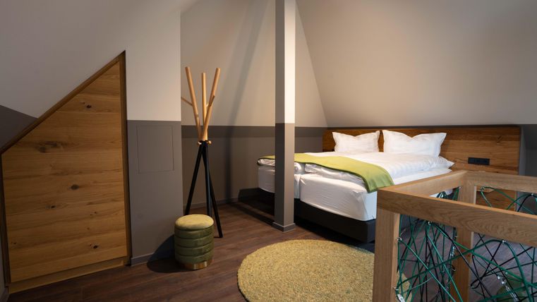 Ein modernes Schlafzimmer mit einem Doppelbett und einer gemütlichen Atmosphäre. Das Zimmer bietet Holzelemente, einen runden Teppich und stilvolle Möbel.