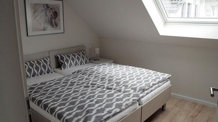 Ein gemütliches Schlafzimmer mit einem großen Doppelbett und modernen Kissen. Das Zimmer hat ein Dachfenster, das natürliches Licht hereinlässt.
