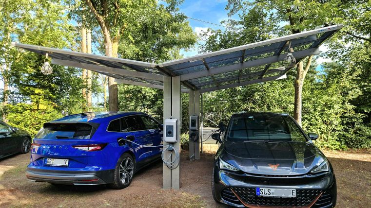 Deux voitures électriques sous un carport. Deux stations de charge avec chacune une puissance de charge AC de 11 kW/h disponibles. Activation et facturation via la réception de l'hôtel. Réservation recommandée.