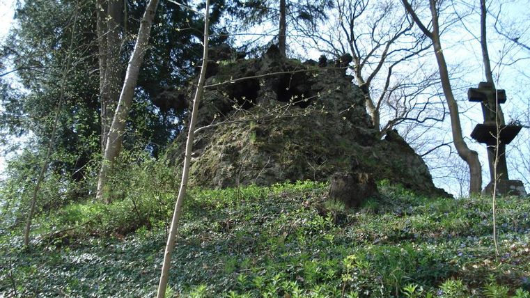 Ein geheimnisvoller Felsen mit grünen Pflanzen und Bäumen. Die Landschaft ist ruhig und einladend.