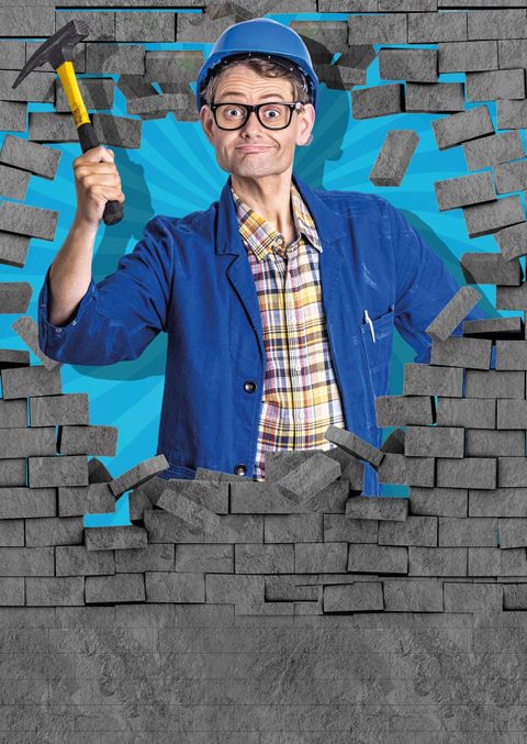 Ein Mann trägt einen blauen Anzug und eine blaue Mütze. Er hält mehrere Kabel in seinen Händen und sieht verwirrt aus.