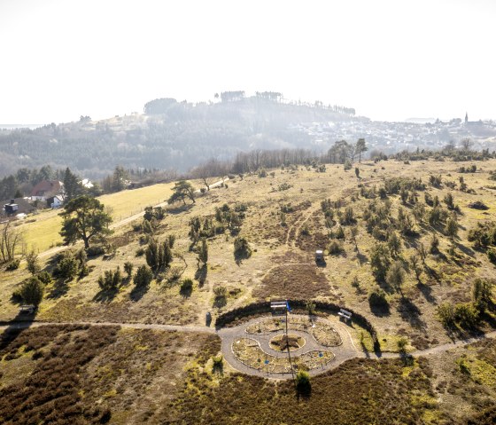 Blick auf eine hügelige Landschaft mit Bäumen und einem kleinen Labyrinth am Wanderweg Traumpfad Wacholderweg., © Eifel Tourismus GmbH, D. Ketz