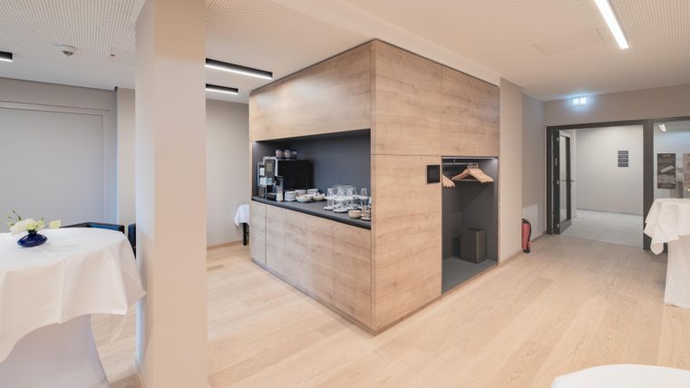 Eine moderne Innenansicht mit einem offenen Raum. In der Mitte befindet sich eine maßgefertigte Küchenzeile aus Holz.