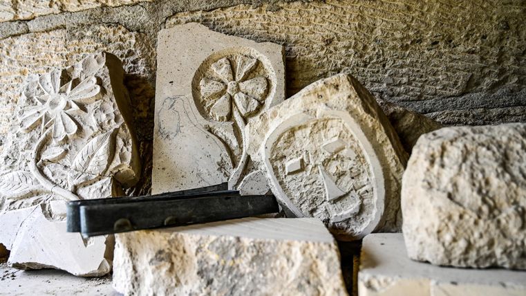 A heap of stone blocks with various embossed motifs. The stones are lying in an old room and showcase artisanal craftsmanship.