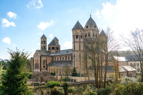 An impressive church with several towers and a historic architectural style. The surrounding landscape is green and inviting.