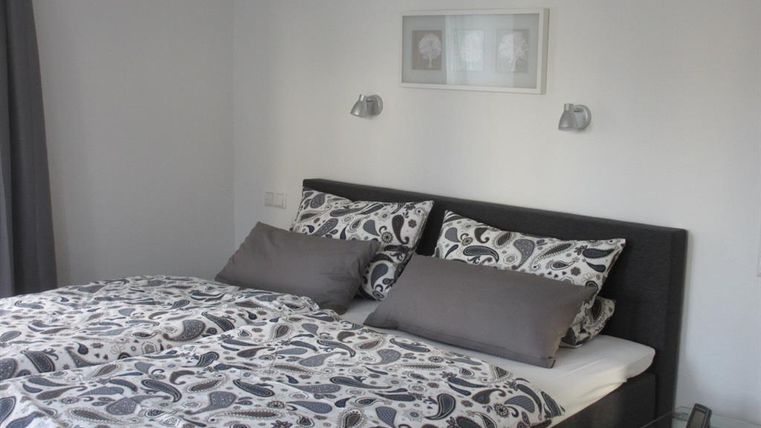 Ein modernes Schlafzimmer mit einem gemütlichen Bett und ansprechender Bettwäsche. Die Wände sind hell und es gibt dekorative Lampen.