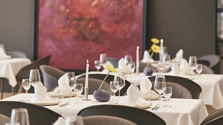 Ein elegantes Restaurant mit schön gedeckten Tischen. Die Atmosphäre ist modern und einladend, mit dekorativen Elementen und sanften Farben.