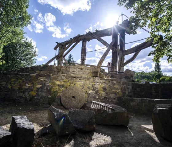 Historische Steinm&uuml;hle mit Holzkonstruktion und M&uuml;hlsteinen, umgeben von B&auml;umen und sonnigem Himmel. Die Szenerie wirkt ruhig und idyllisch., &copy; Klaus-Peter Kappest/Vulkanregion Laacher See