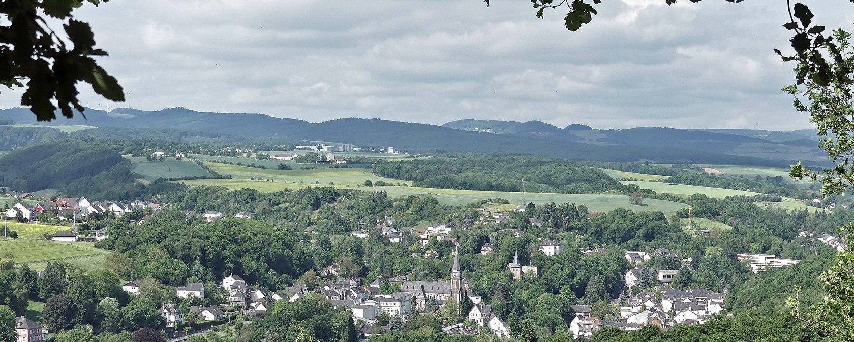 Panoramablick auf Burgbrohl mit Kirche im Zentrum, umgeben von gr&uuml;ner Landschaft und H&uuml;geln., &copy; Werner M&uuml;ller