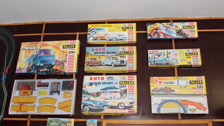 Eine Sammlung von Modellauto-Bausätzen in bunten Verpackungen. Die Modelle sind auf einer Wand montiert und zeigen verschiedene Autos und Rennstrecken.